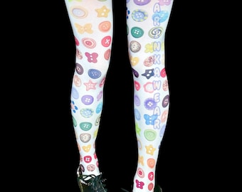 Puede incluir: Medias blancas con un estampado colorido de varios botones en formas de círculos, estrellas y flores. La pierna derecha muestra el texto vertical D A R K N E S S W E A R en letras azules. Las medias se combinan con una falda de cuadros vichy rosa.