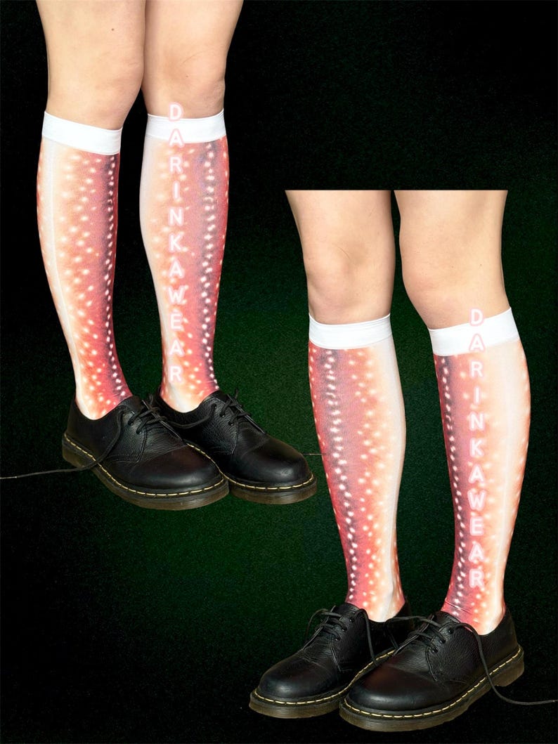 May include: Knee-high socks with a salmon-coloured pattern and white polka dots. The socks feature the text "DRINKAWEAR" printed vertically. Black leather shoes are worn with the socks.