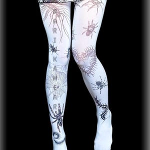 May include: White tights with a black spider and web design. The tights feature various spider illustrations, spiderwebs, and the text "ARIKAWA". The design covers the entire tights, creating a spooky and unique look.
