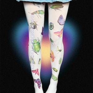 Può includere: Collant bianchi con illustrazioni di insetti colorati, tra cui coleotteri e farfalle. Il testo "DAIN WEAR" è stampato verticalmente sulla gamba sinistra. I collant sono indossati con una gonna di jeans.