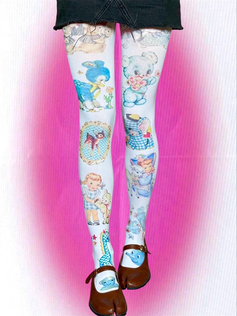 May include: White tights featuring a repeating pattern of vintage-style illustrations including blue teddy bears, a fawn in an oval frame, a child with a lamb, a blue elephant, and a small blue dinosaur, paired with brown split-toe shoes.