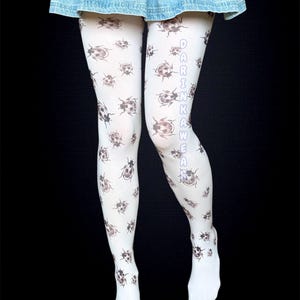 May include: White tights with a repeating pattern of brown ladybugs. The text "DARINKAWAE" is printed vertically down the side of one leg. The tights are worn with a denim skirt.