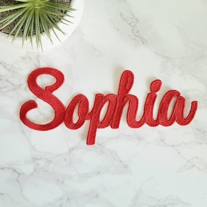 May include: Red embroidered fabric patch with the name "Sophia" in a cursive font.