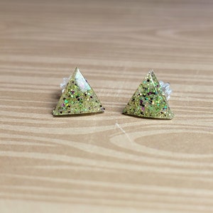 May include: A pair of triangle-shaped earrings with green glitter embedded in clear resin.