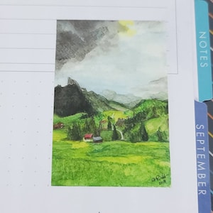 May include: Watercolor painting of a green valley with a mountain range in the background. The sky is cloudy with a hint of sun shining through. There are small houses and trees in the valley. The painting is signed "J. R. 2018".