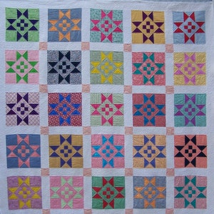 May include: A quilt with a patchwork design featuring a variety of colors and patterns. Each square is a different design with a star in the center. The quilt is made up of 36 squares.