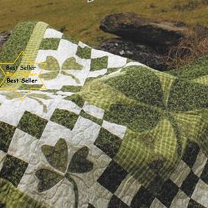 Op de afbeelding: Een groen en wit quilt met een geruit patroon en een groot klaverbladontwerp. De quilt heeft de tekst "Best Seller" erop gedrukt.