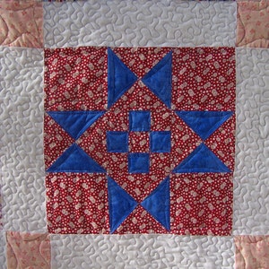 May include: A quilt block with a red, white, and blue star pattern. The star is made up of four blue triangles and a white square in the center. The background is a red fabric with white polka dots.
