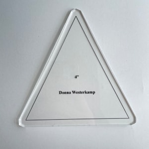 May include: A clear plastic triangle ruler with a 4-inch measurement and the name "Donna Westerkamp" printed on it.