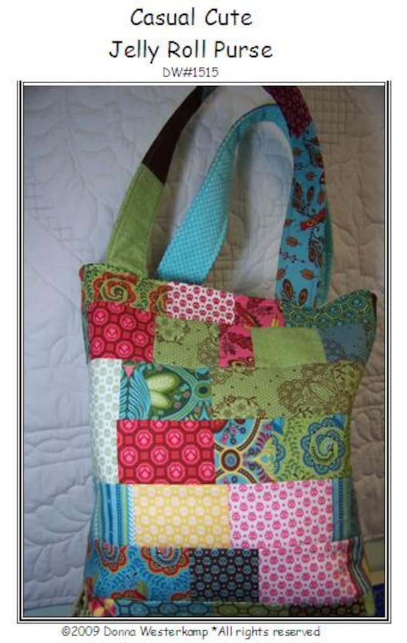 K&ouml;nnte beinhalten: Eine bunte Patchwork-Tragetasche mit einem blauen, gr&uuml;nen und rosa Design. Die Tasche hat eine gro&szlig;e, rechteckige Form und zwei Henkel. Der Text "Casual Cute Jelly Roll Purse DW#1515" ist oben auf dem Bild gedruckt.