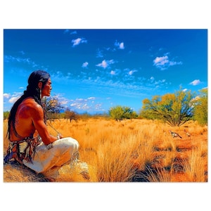 May include: A Native American man wearing traditional clothing sits in a field of long grass, gazing towards the distant horizon. The sky is blue with white clouds, and there are a few trees in the background.