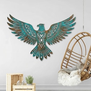 May include: A large metal wall art piece depicting an eagle with outstretched wings. The eagle is teal and brown with intricate geometric patterns. The artwork is mounted on a white wall, creating a striking contrast.