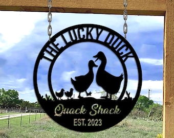 May include: Black metal sign with the text "The Lucky Duck Quack Shack Est. 2023" and a silhouette of a family of ducks.