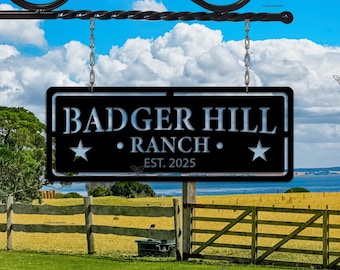 May include: Black metal Badger Hill Ranch sign with white lettering, two stars, and the establishment year 2025. The sign hangs from a decorative wrought iron bracket against a blue sky with clouds.