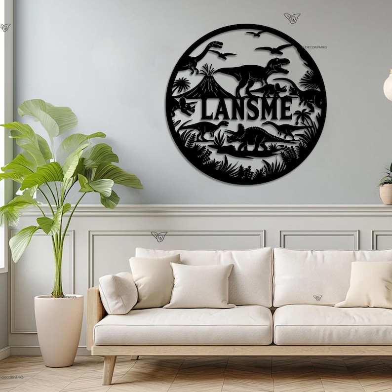 May include: Black metal wall art featuring a circle with dinosaurs and the name "LANSM E" in the center. The art is hanging on a white wall above a white couch.