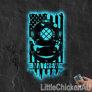 May include: A blue and black personalized night light featuring a diving helmet and an American flag design. The name "MATTHEW" is displayed below the helmet.
