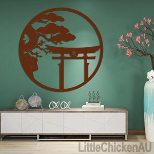 May include: A brown metal wall art piece featuring a circular design with a Japanese Torii gate, a tree, and the Japanese character for "way". The artwork is mounted on a teal wall, with a white and wood-toned cabinet below.
