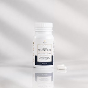 May include: A white plastic bottle of Grasole Night Magnesium food supplement with a dark blue label. The label features the text "NIGHT MAGNESIUM," "Premium Magnesium Complex," and "60 capsules." Two white capsules are placed next to the bottle.