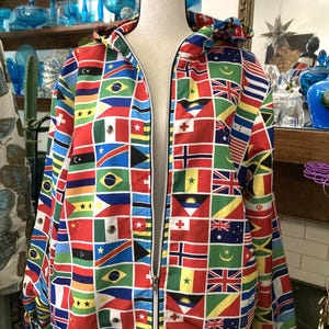 May include: A hooded jacket featuring a vibrant patchwork design of international flags. The jacket has a full zipper and is displayed on a mannequin. The flags are arranged in a grid pattern, with a variety of colors and designs.