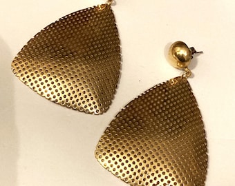 May include: A pair of gold-toned earrings. Each earring features a small, round stud at the top, connected to a large, triangular pendant. The pendants are made of a perforated metal, creating a textured surface. The earrings are designed for pierced ears.