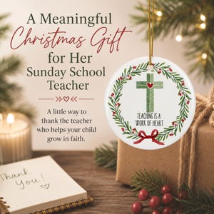 May include: A round white ceramic ornament featuring a green cross with a small red heart at its center, surrounded by a wreath of green leaves and red berries. A red ribbon bow is at the bottom, with the text "TEACHING IS A WORK OF HEART" below the cross.