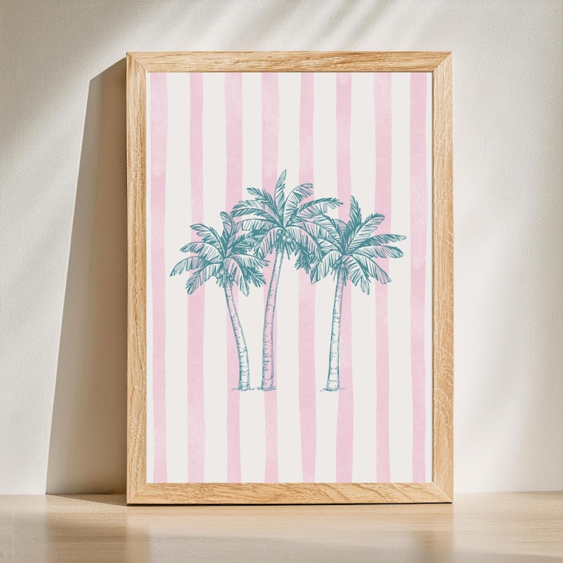 May include: A framed art print featuring three teal palm trees on a background of pink and white vertical stripes. The artwork is set in a light brown wooden frame, suitable for wall decor.