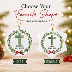 May include: Two white ceramic ornaments, one circular and one snowflake-shaped, each featuring a green cross with a red heart, surrounded by a holly wreath and the text 'TEACHING IS A WORK OF HEART'. Both hang from gold strings.