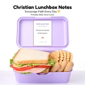 May include: A lilac lunchbox containing a sandwich, waffle fries, and breadsticks. A card inside displays the message "God Loves You!" and a Bible verse. The text above reads "Christian Lunchbox Notes" and "Encourage Faith Every Day."