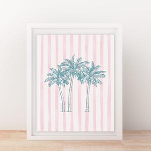 May include: Framed art print featuring three teal palm trees on a pink and white striped background. The artwork is encased in a white frame, creating a clean and modern aesthetic. This piece is perfect for adding a touch of tropical flair to any space.