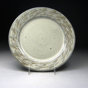 May include: A white ceramic plate with a raised design of brown leaves around the rim.