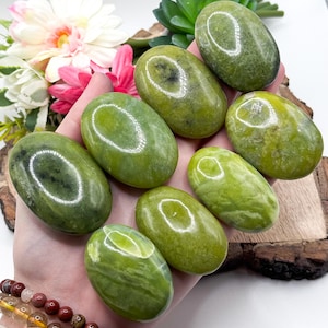 May include: A collection of eight smooth, green serpentine stones, each with a unique pattern and polished to a high shine. The stones are oval-shaped and have a natural, earthy appearance.