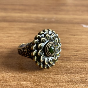 a silver ring with a green stone in the center