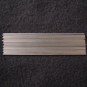 May include: A bundle of 20 silver-colored metal knitting needles. The needles are arranged in a row on a dark gray surface.