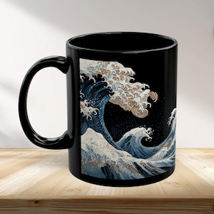 Puede incluir: Taza de cerámica negra con un diseño de ola japonesa en tonos azules, blancos y beige. La obra de arte representa una gran ola con detalles intrincados sobre un fondo oscuro. La taza tiene un asa curvada.