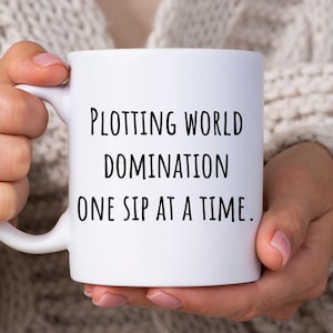 May include: White ceramic coffee mug with black text that reads "Plotting world domination one sip at a time."