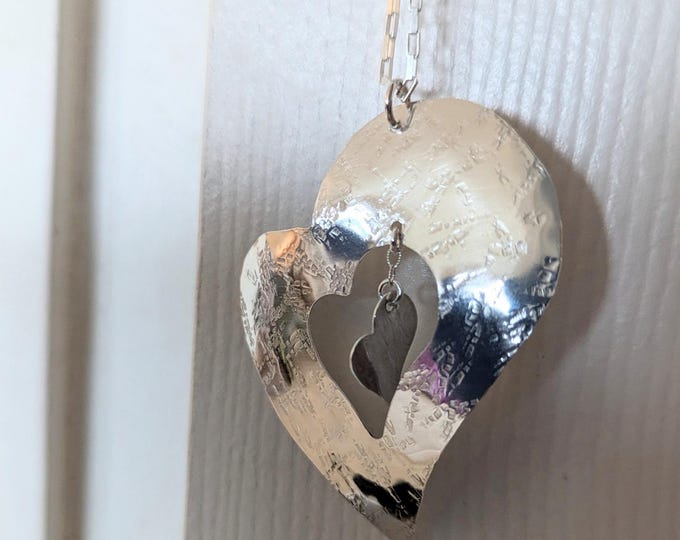 Sterling raw silk textured heart with floating heart dangles on tiny chain.  from french Slight concave form.