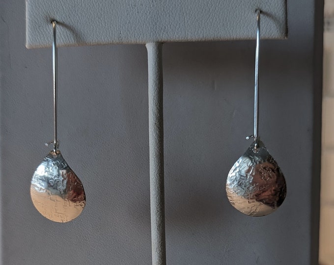 Sterling raw silk textured small teardrop earrings dangle from kidney wires.  Slight convex form.