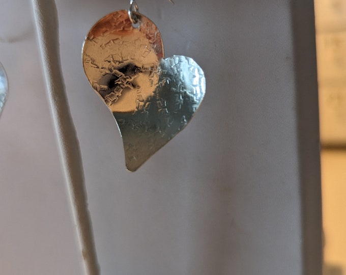 Sterling raw silk textured small hearts dangle from french wires.  Slight concave form.