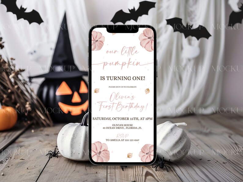 K&ouml;nnte beinhalten: Ein Smartphone zeigt eine Einladung zum Thema Halloween mit dem Text "our little pumpkin is turning one!" in rosa Schrift. Die Einladung enth&auml;lt den Namen "Olivia" und Veranstaltungsdetails. Der Hintergrund zeigt K&uuml;rbisse, Flederm&auml;use und einen Hexenhut.