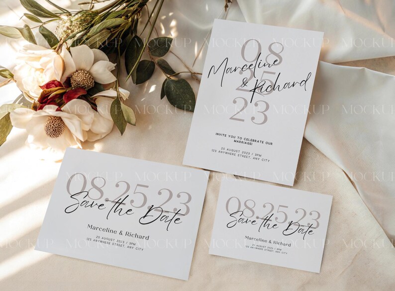 May include: Three white wedding invitation cards with the text "08.25.23" and "Save the Date" or the names "Marceline & Richard". The cards are arranged on a light-colored surface with floral decorations.