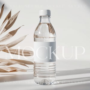 May include: A clear plastic water bottle with a white label. The bottle is sitting on a white surface with a dried palm leaf in the background.