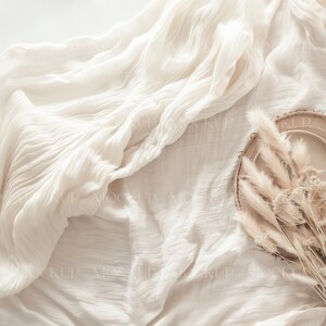 May include: A white plate with a wooden rim sits on a white fabric background. Dried pampas grass is arranged around the plate.