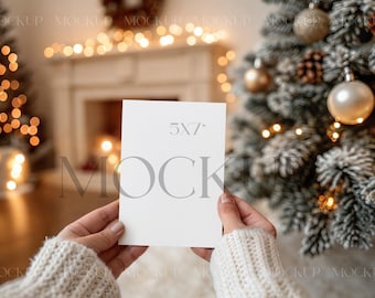 May include: A blank 5x7 inch card is held in front of a Christmas tree and fireplace. The card is white with the text "5x7" printed on it. The background includes a decorated Christmas tree with ornaments and lights, and a fireplace with a wreath.