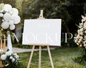 以下が含まれることがあります： 「36x24」の文字と大きなフォントで「MOCKUP」という言葉が書かれた、木製のイーゼルに置かれた白い看板。イーゼルは、白い風船と花が背景にある芝生の屋外に設置されています。