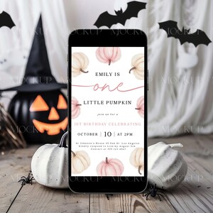 K&ouml;nnte beinhalten: Ein Smartphone zeigt eine Halloween-Einladung mit K&uuml;rbisillustrationen. Die Einladung lautet "Emily is one, Little Pumpkin, 1st Birthday Celebrating October 10 at 2 PM." Die Szene umfasst K&uuml;rbisse, Flederm&auml;use und eine Jack-o'-Laterne.