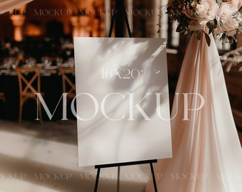 May include: A white sign on an easel with the text "16x20" and the word "MOCKUP" printed on it. The sign is in front of a draped fabric and a floral arrangement.
