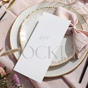 May include: A mock-up of a place setting with a white plate with gold trim, a pink napkin, and gold and black silverware. A white card with the text "4x9" is on the plate. The setting is on a pink tablecloth.