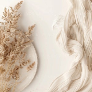 May include: A white ceramic plate with dried beige pampas grass on a white background. A white fabric with a textured surface is in the upper right corner of the image.