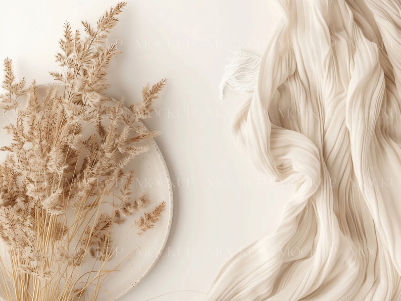 May include: A white ceramic plate with dried beige pampas grass on a white background. A white fabric with a textured surface is in the upper right corner of the image.