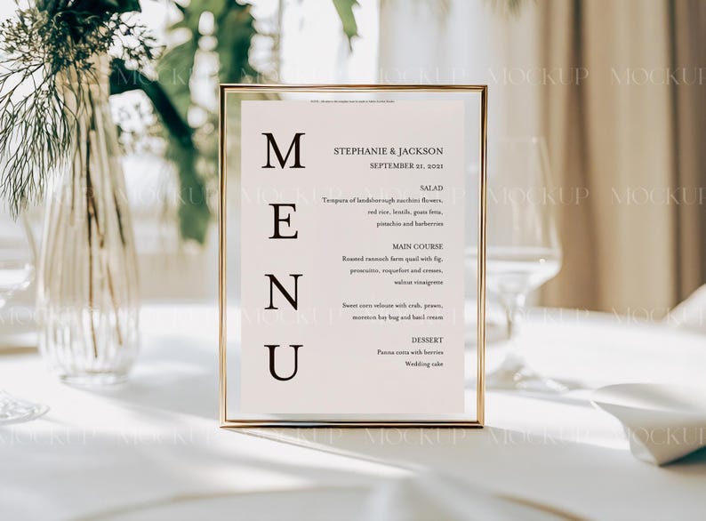 May include: A gold-framed menu sign with a white background and black text. The menu lists the names Stephanie & Jackson, the date September 21, 2021, and the menu items: Salad, Main Course, and Dessert.